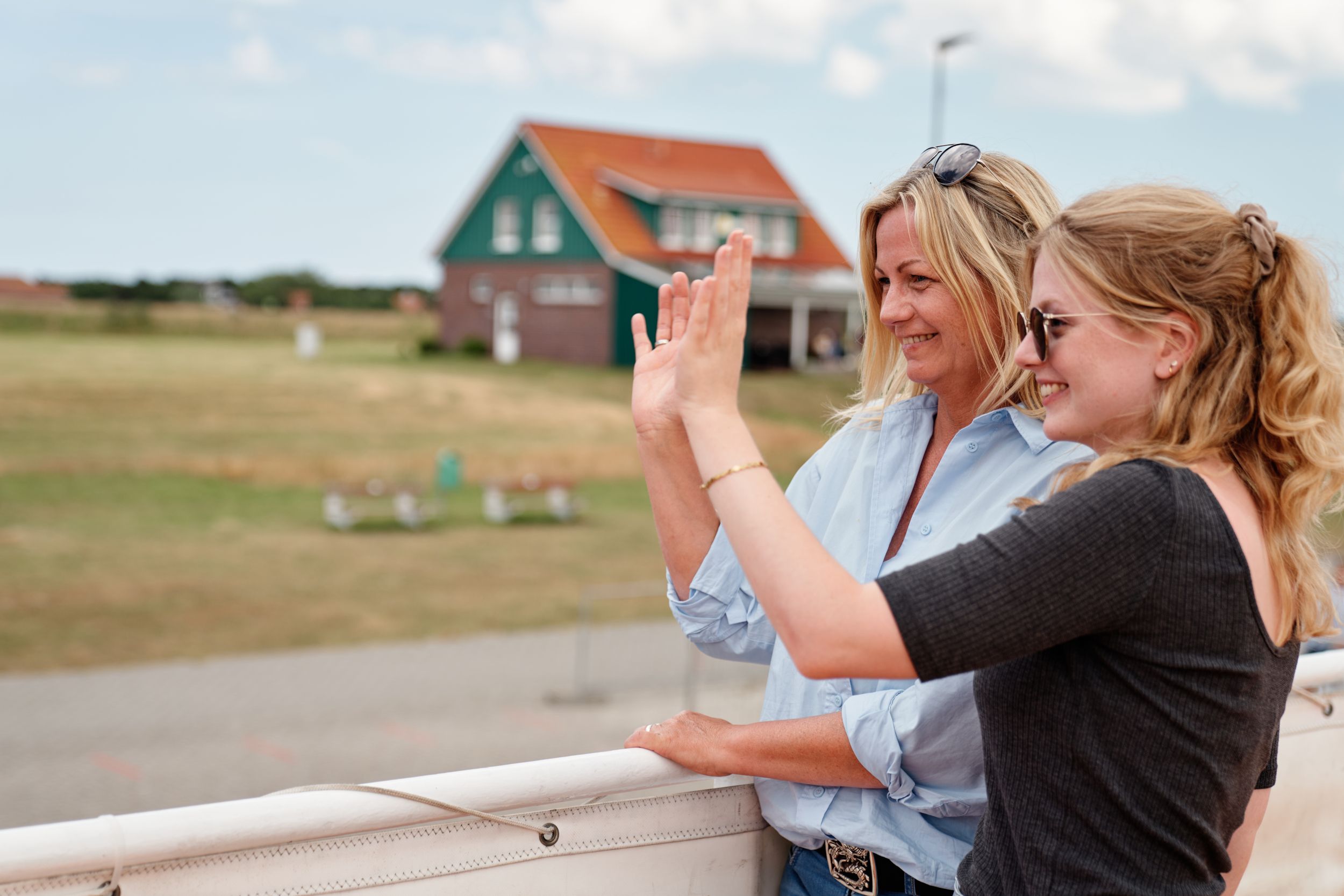 Zwei Frauen winken bei ihrer Ankunft am Hafen Spiekeroog