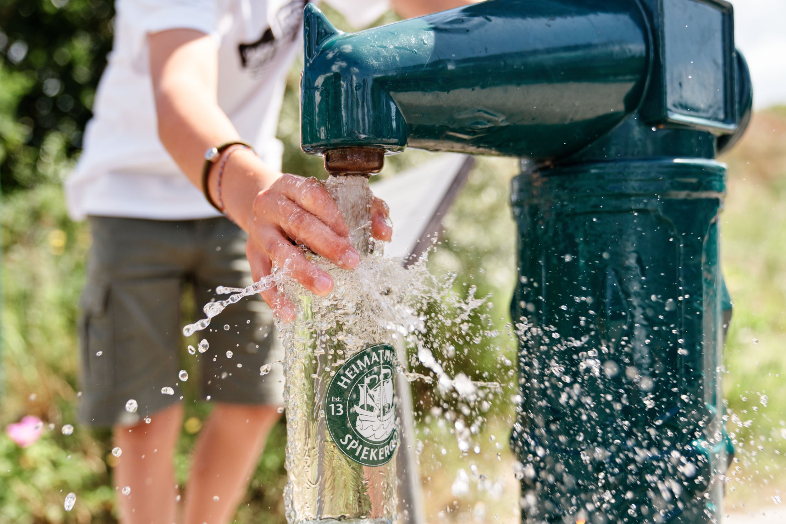 Nachfüllen einer Trinkflasche von Spiekroog am Trinkbrunnen 